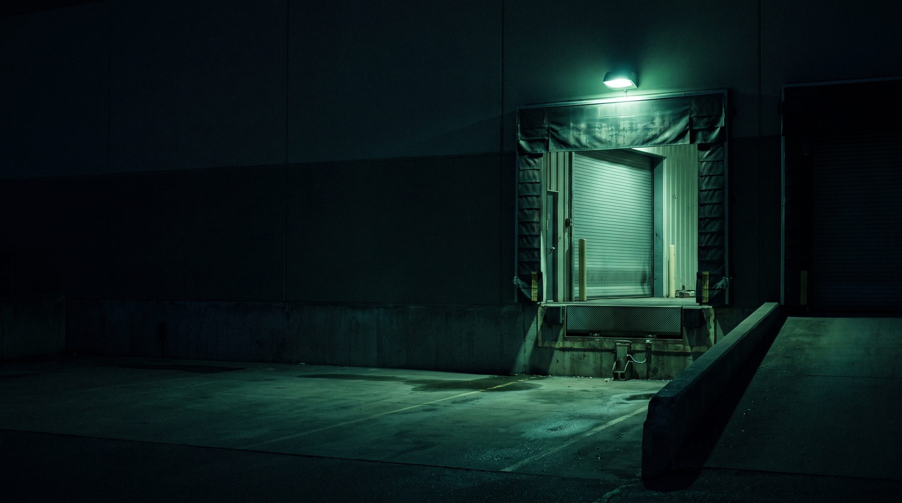 Empty loading dock at dusk, roller door up, lit from inside