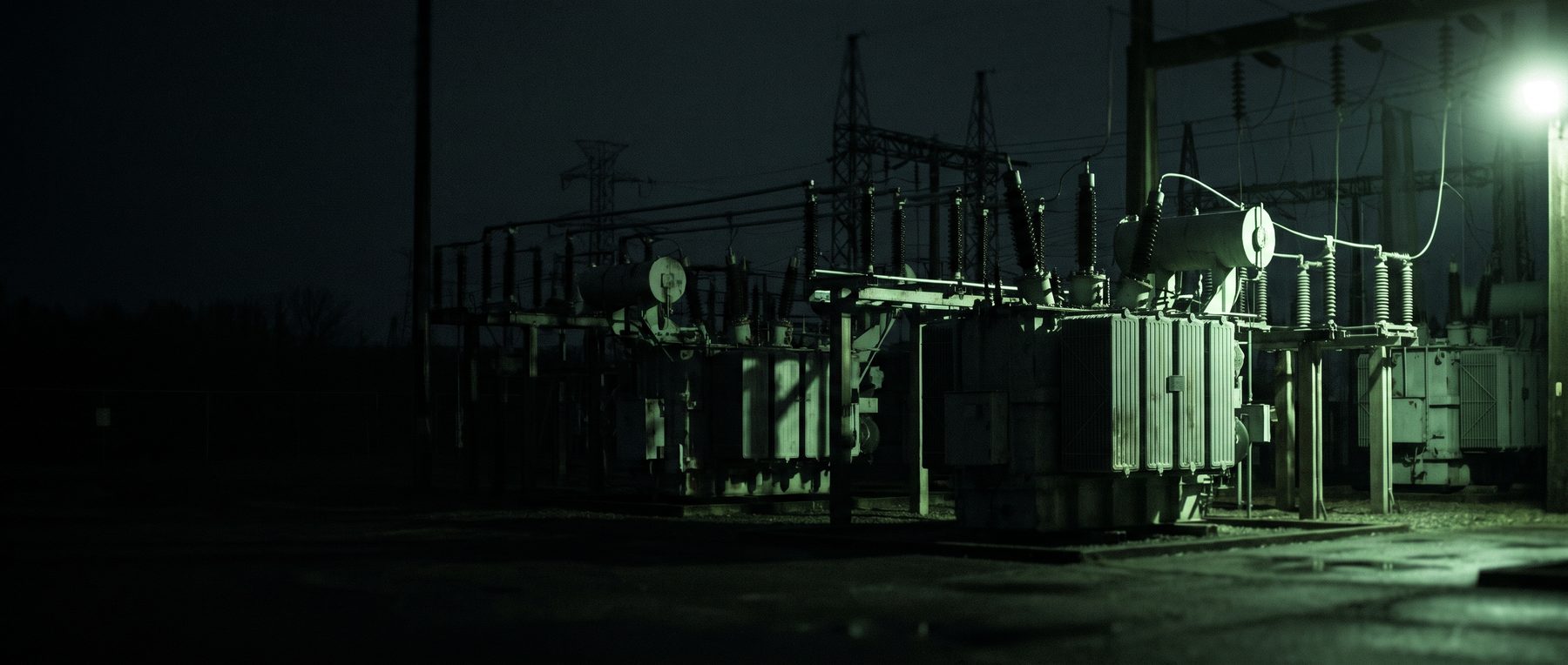 Substation yard at dusk, wide. Transformer bank, bus work, no people